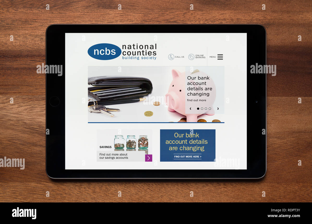 The website of National Counties Building Society is seen on an iPad tablet, which is resting on a wooden table (Editorial use only). Stock Photo