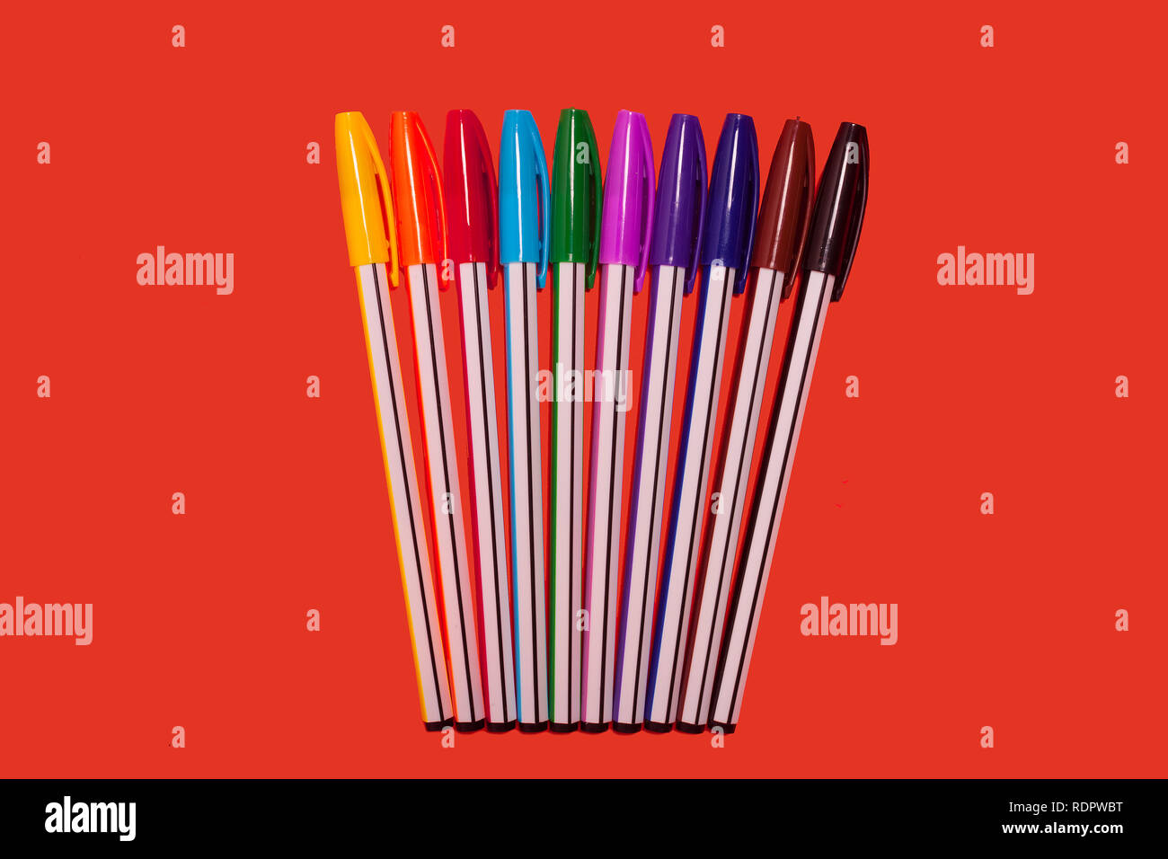 colored pens lying on a red background Stock Photo