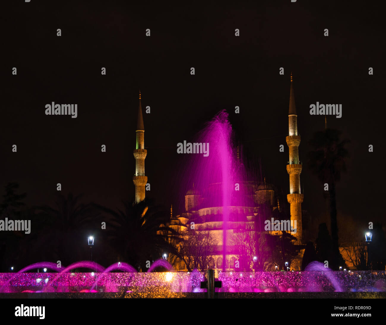 A colorful fountain from a fountain at night in front of the mosque ...