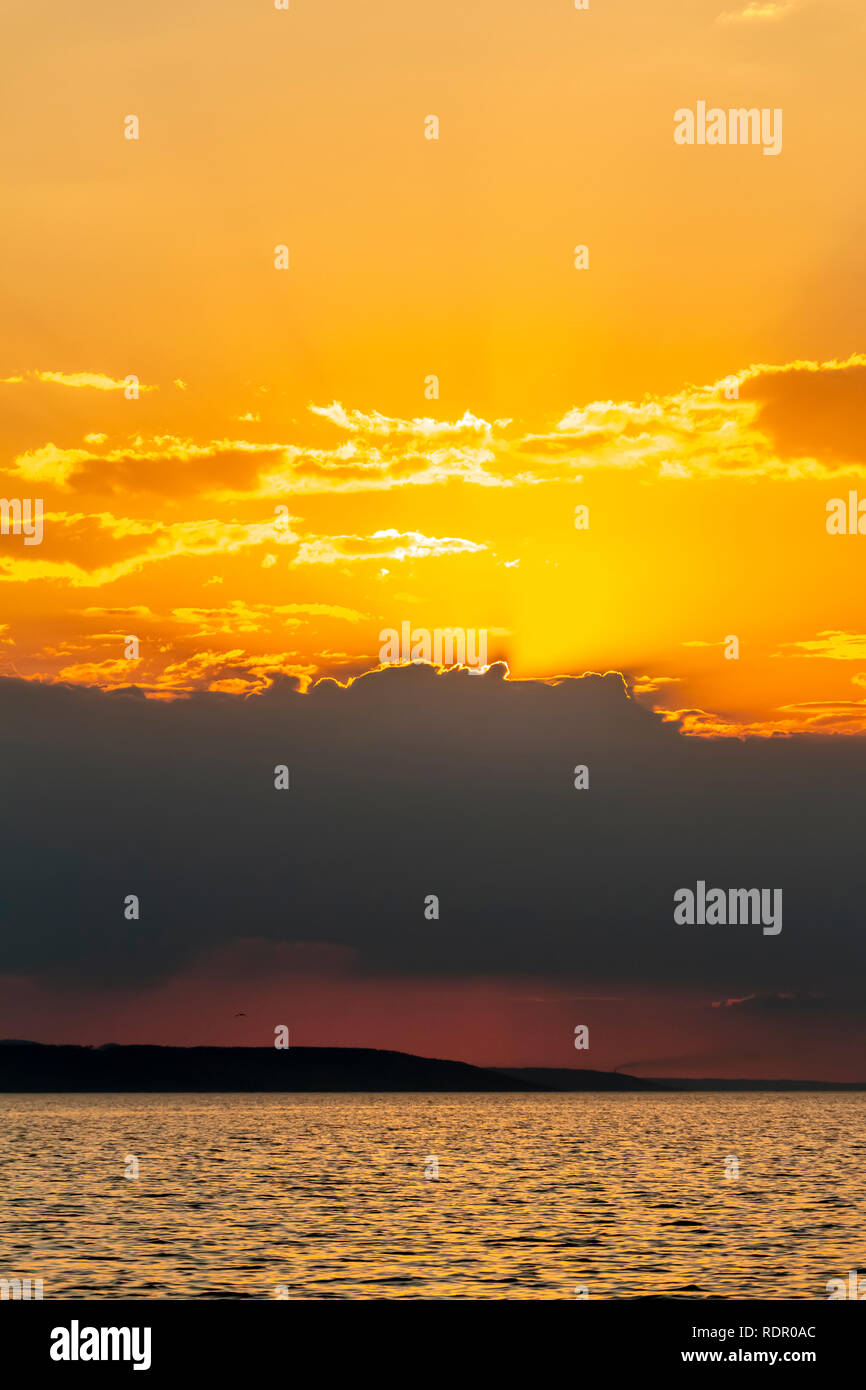 Golden Sunset into the sea with the silhouette of an island Stock Photo ...