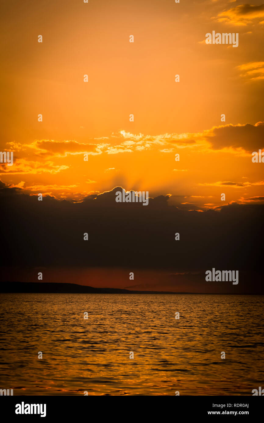 Golden Sunset into the sea with the silhouette of an island Stock Photo ...