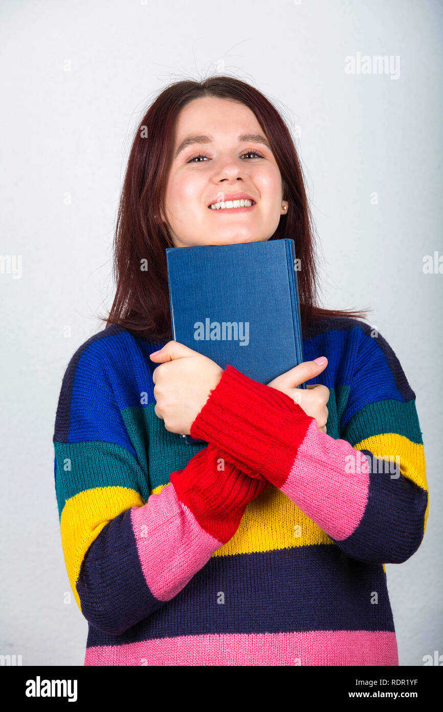 Cheerful woman student hugging a book and smile to camera isolated on ...