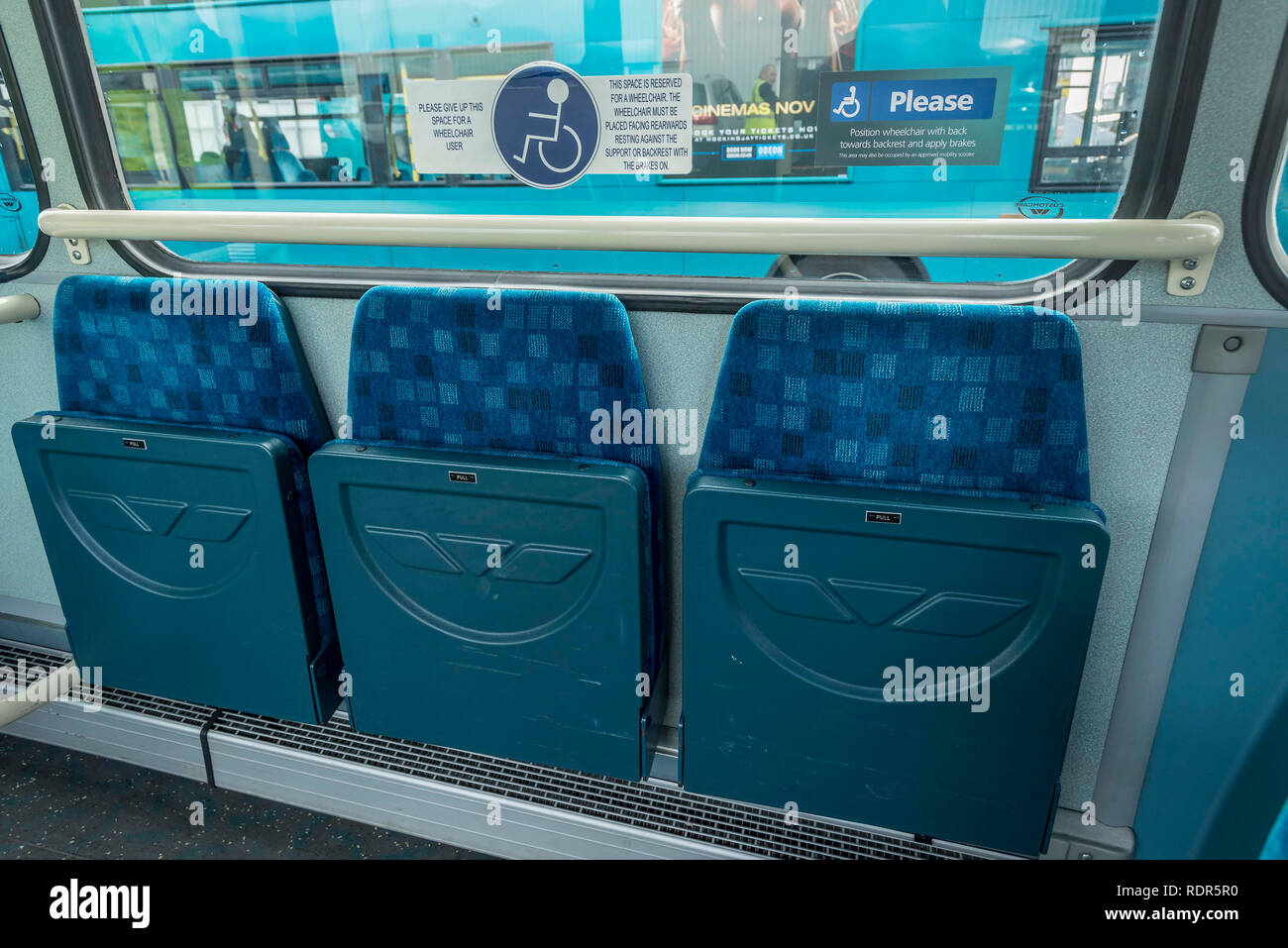 Bus flip-up seats in wheekchair area. Stock Photo