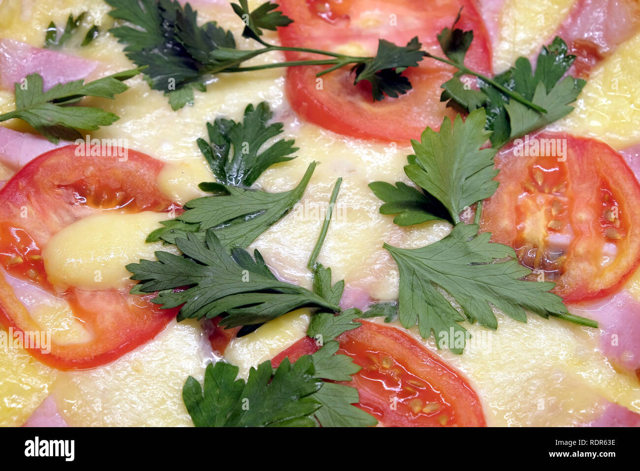 Closeup fragment of plate with prepared appetizing pizza with tomatoes, bacon and cheese as background top view Stock Photo
