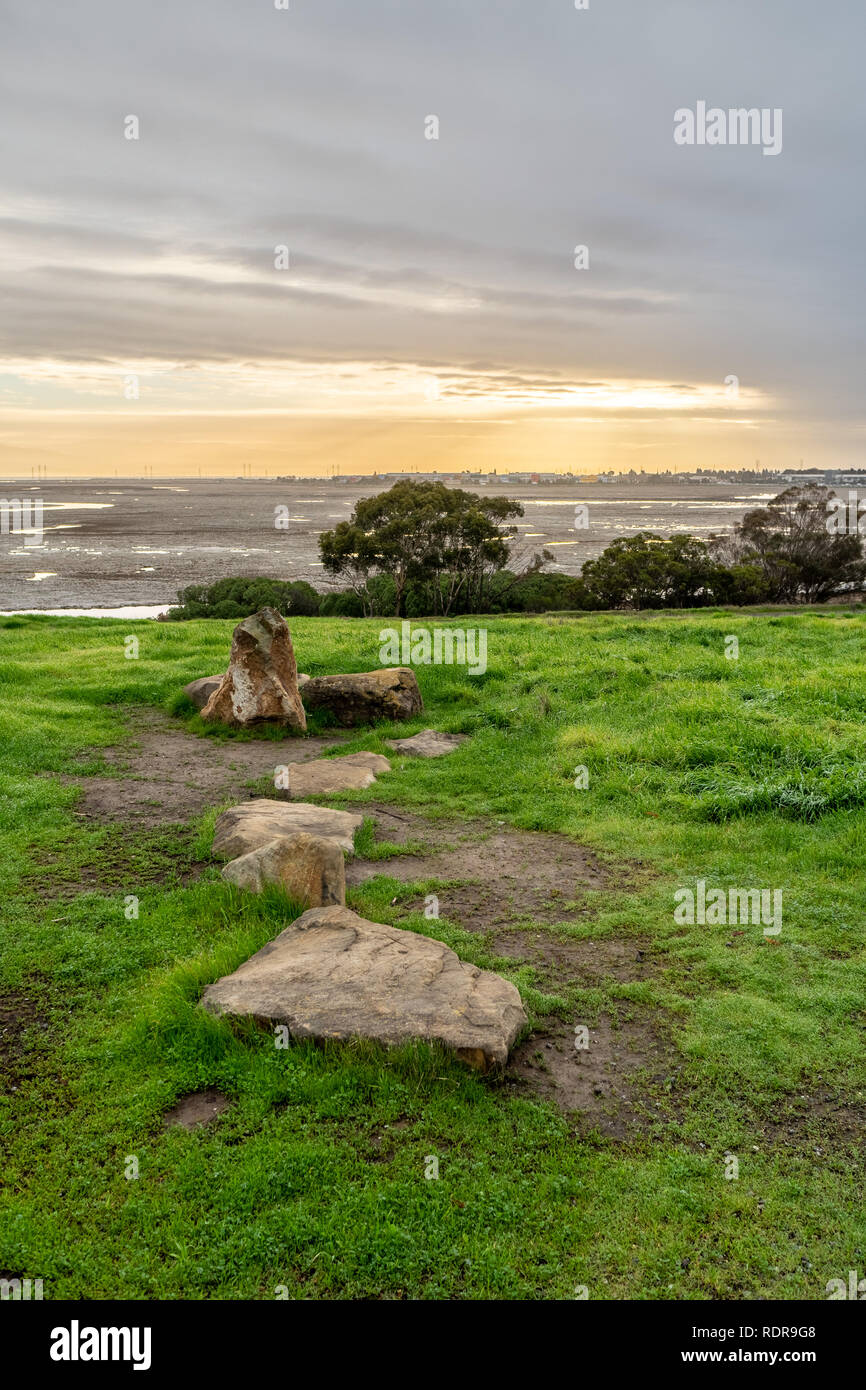 Rocks and grass on a hilly terrain with the sizing sun peeking through ...