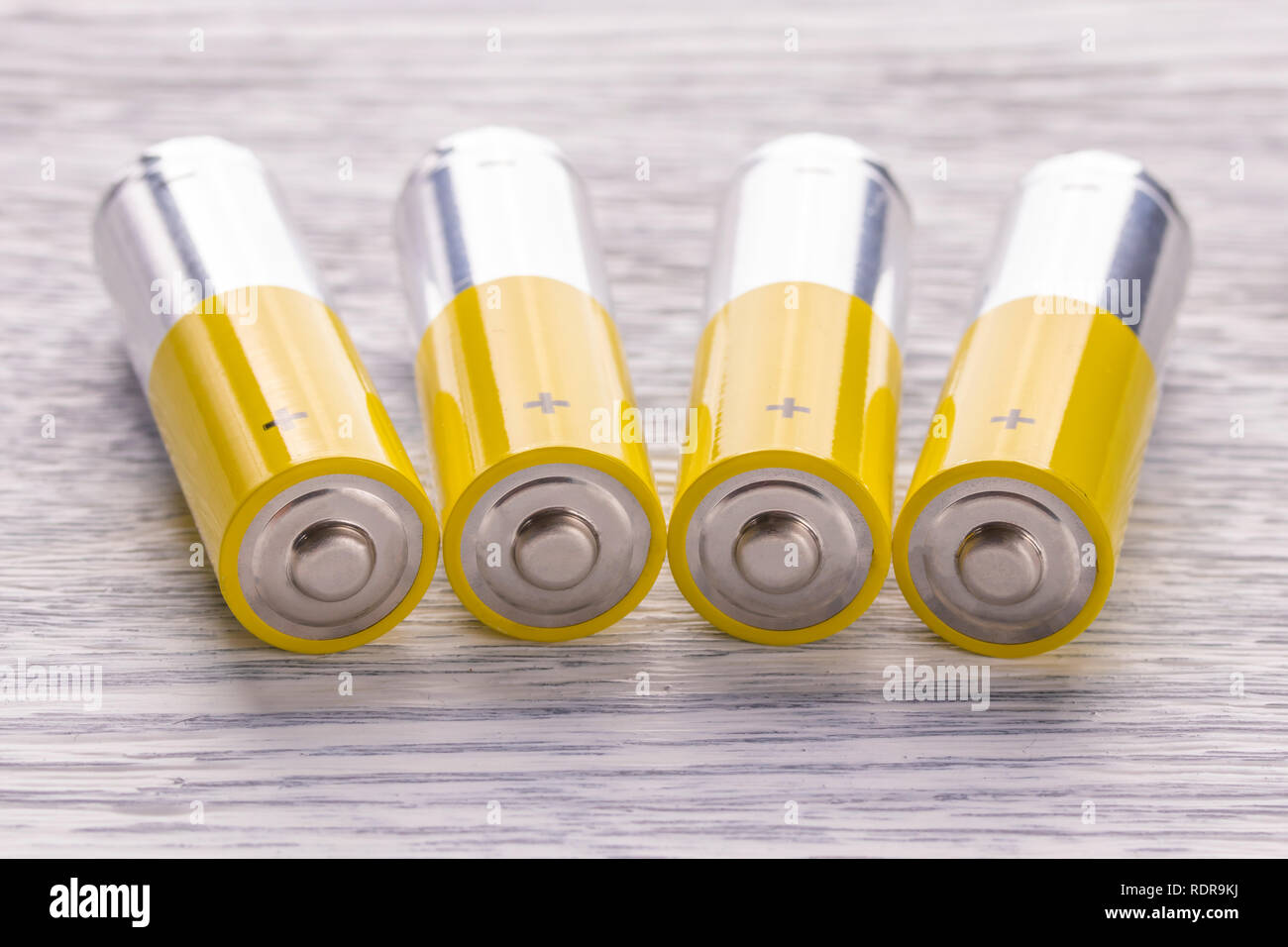 AA batteries lie on an old white wooden table. Energy concept Stock