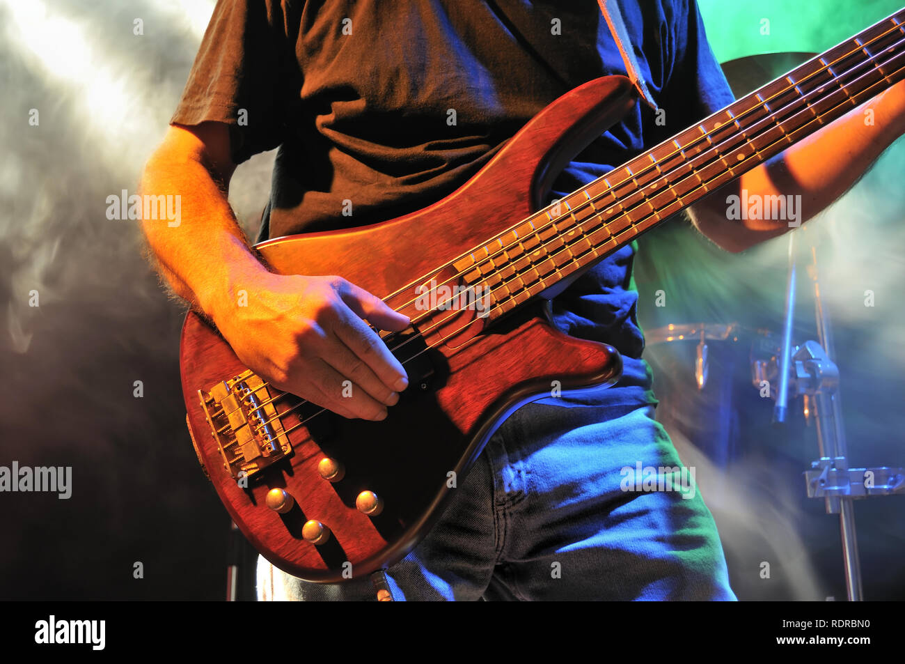 Electric bass guitar player playing on stage with smoke and lights