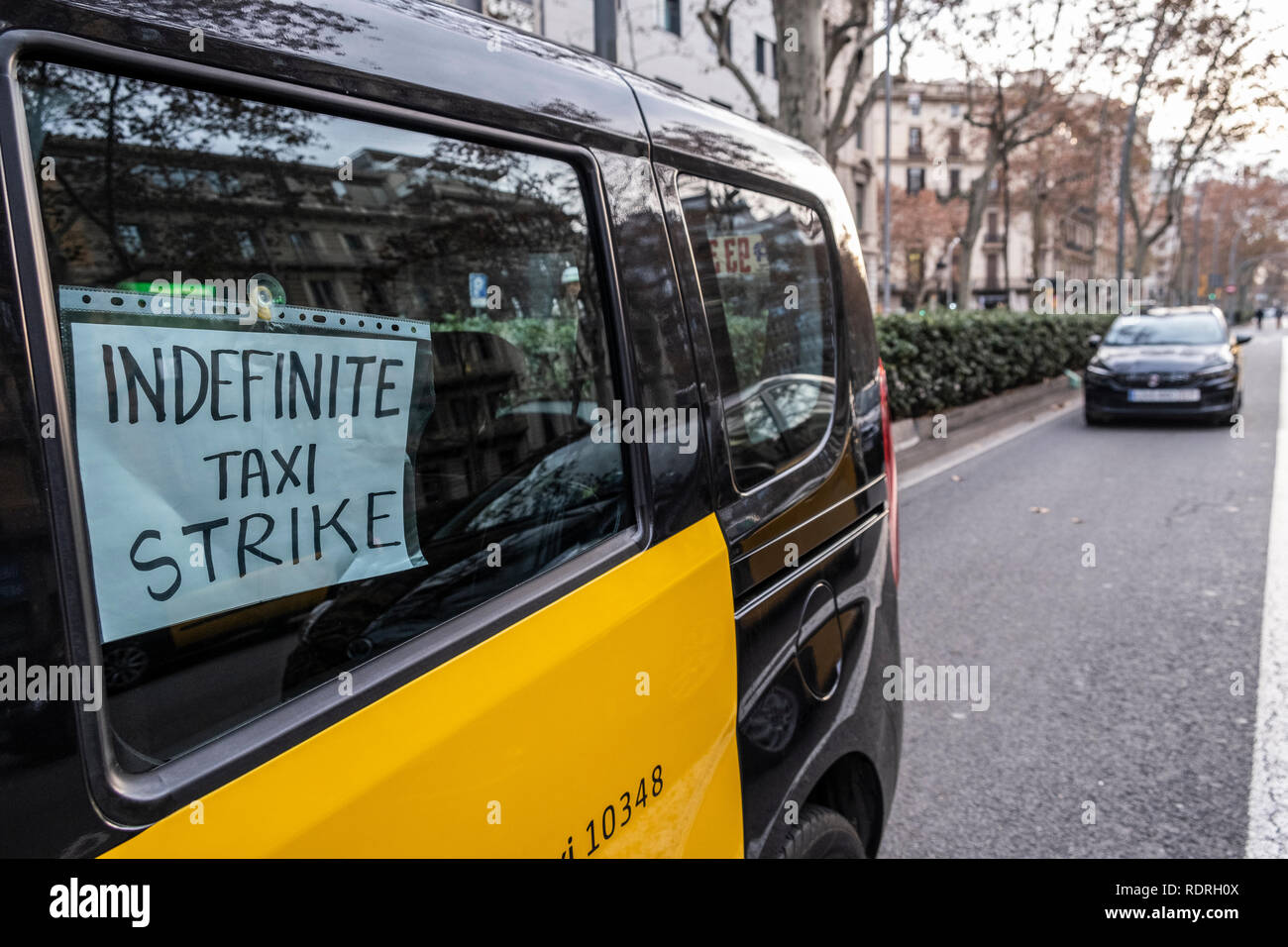 A taxi is seen with a placard saying Indefinite Taxi Strike. After broken negotiations with the Government of Catalonia, the taxi drivers of Barcelona return to the indefinite strike by occupying the Gran Vía of Barcelona. Taxi drivers have been touring the center of Barcelona in a demonstration where there have been attacks against Uber and Cabify drivers with a VTC license. Stock Photo