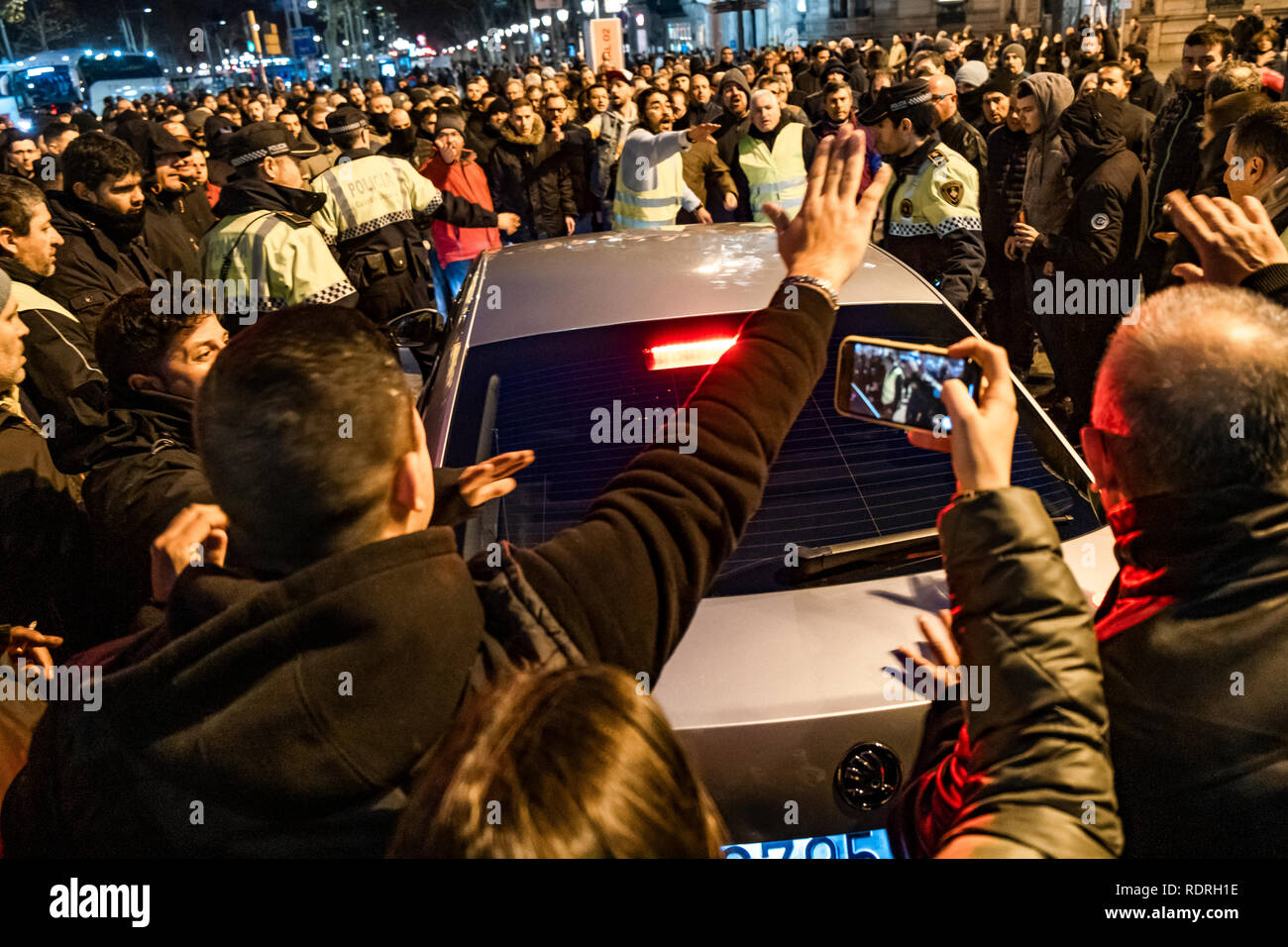 A group of taxi drivers is seen harassing a vehicle with a VTC license during the protest. After broken negotiations with the Government of Catalonia, the taxi drivers of Barcelona return to the indefinite strike by occupying the Gran Vía of Barcelona. Taxi drivers have been touring the center of Barcelona in a demonstration where there have been attacks against Uber and Cabify drivers with a VTC license. Stock Photo