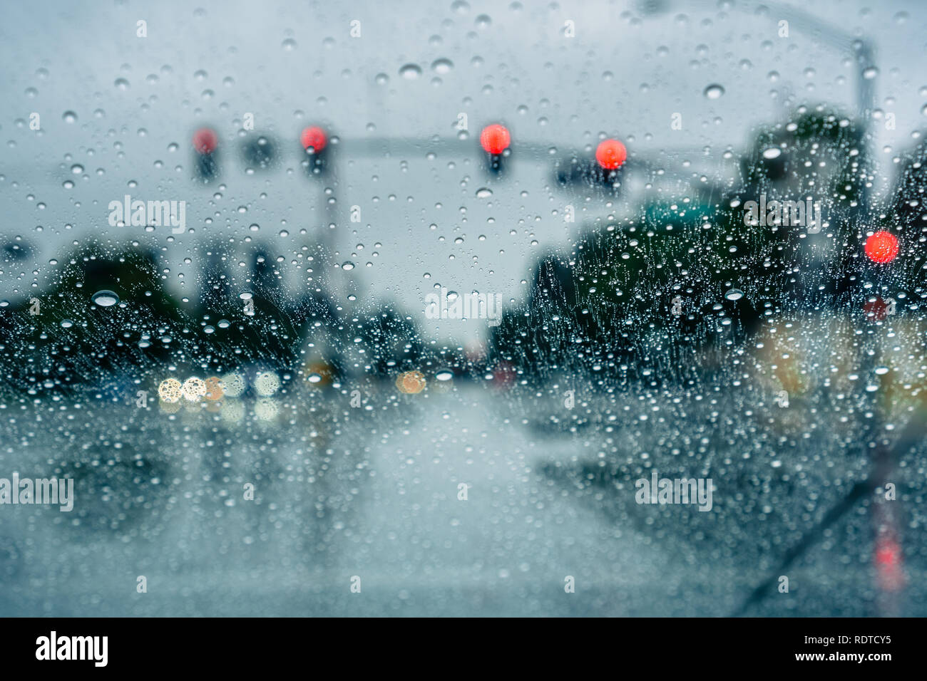 Waiting at a traffic junction for the green light during a rainy day; raindrops on the windshield Stock Photo