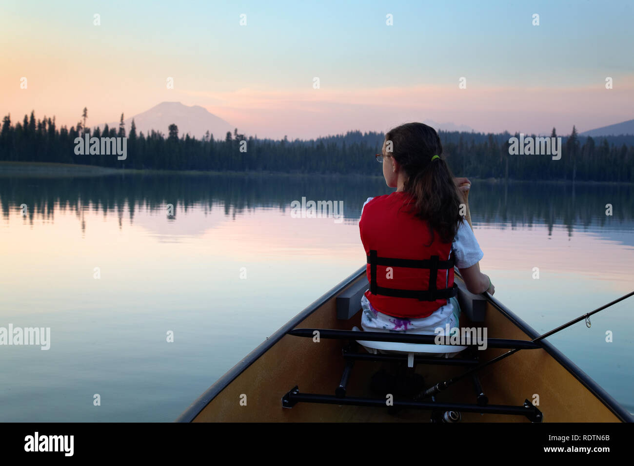 Girl paddling canoe on Hosmer Lake at dusk, Mountain Bachelor in background, Cascade Lakes, Oregon, USA Stock Photo