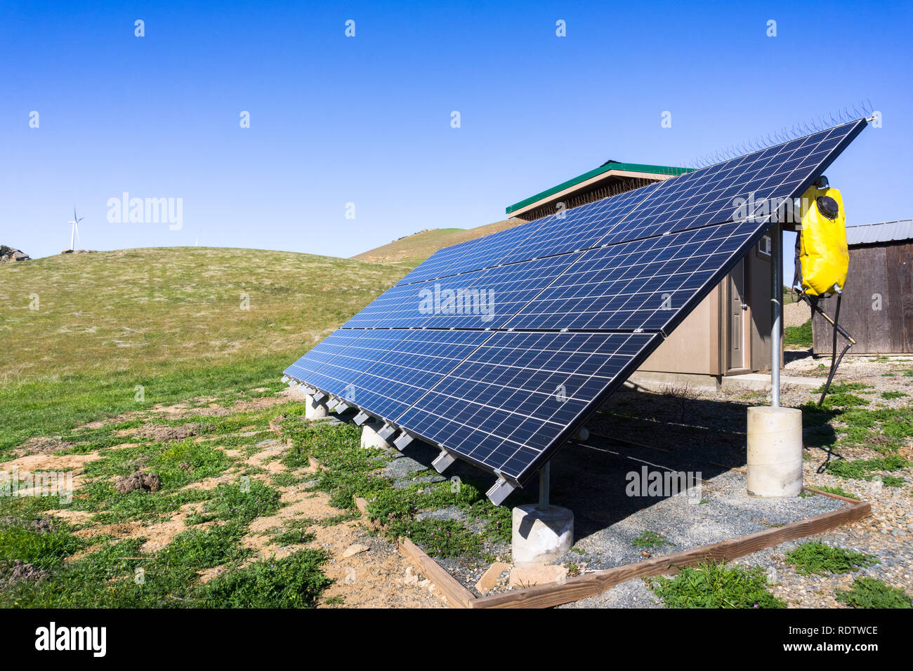 Solar panels on the hills of east San Francisco bay area; wind turbines in the background; California Stock Photo