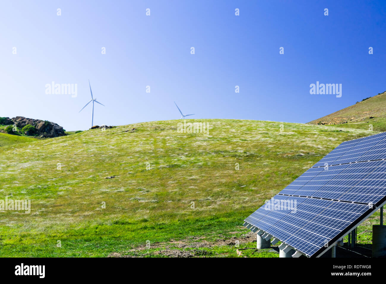 Solar panels on the hills of east San Francisco bay area; wind turbines in the background; California Stock Photo