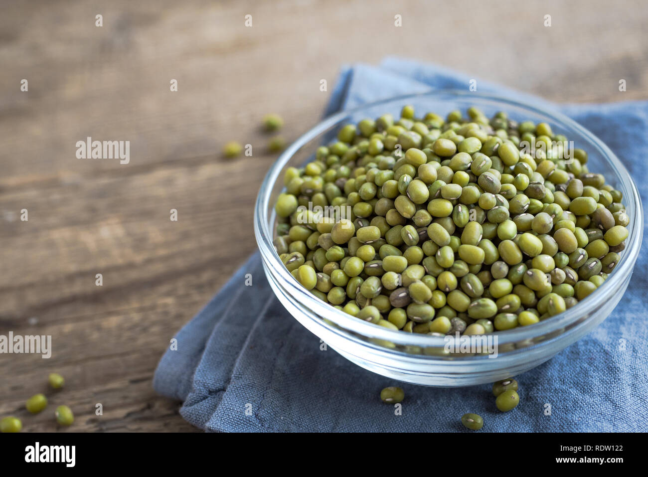 Mung beans in bowl on wooden table, ready to cook, close up. Stock Photo