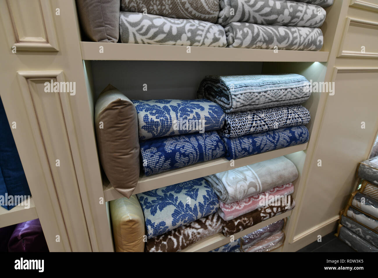 Many blankets and decorative pillows on shop window Stock Photo