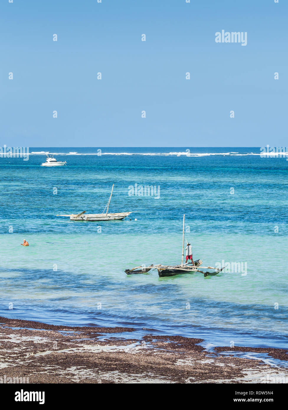 DIANI BEACH, KENYA - OCTOBER 14, 2018: Unindentified African man and his traditional wooden boat on Diani beach, Kenya Stock Photo
