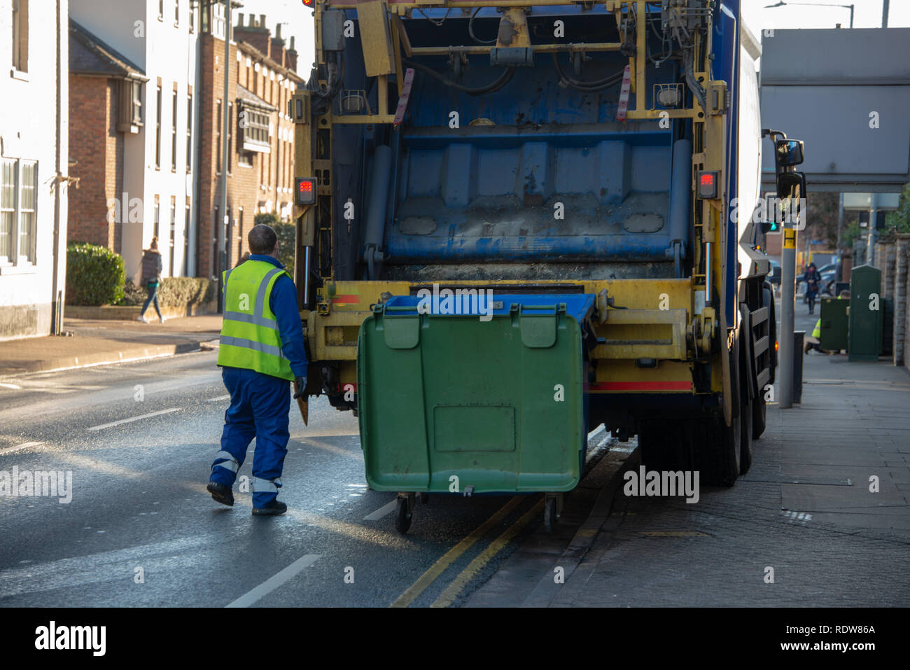 bin lorry or waster truck collects refuse from a green dumpster with council bin worker