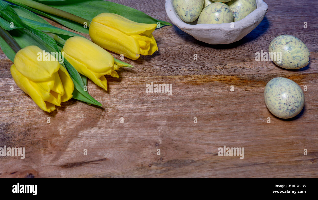 Wooden copy space decorated with yellow tulips and Quail eggs  - top view Stock Photo
