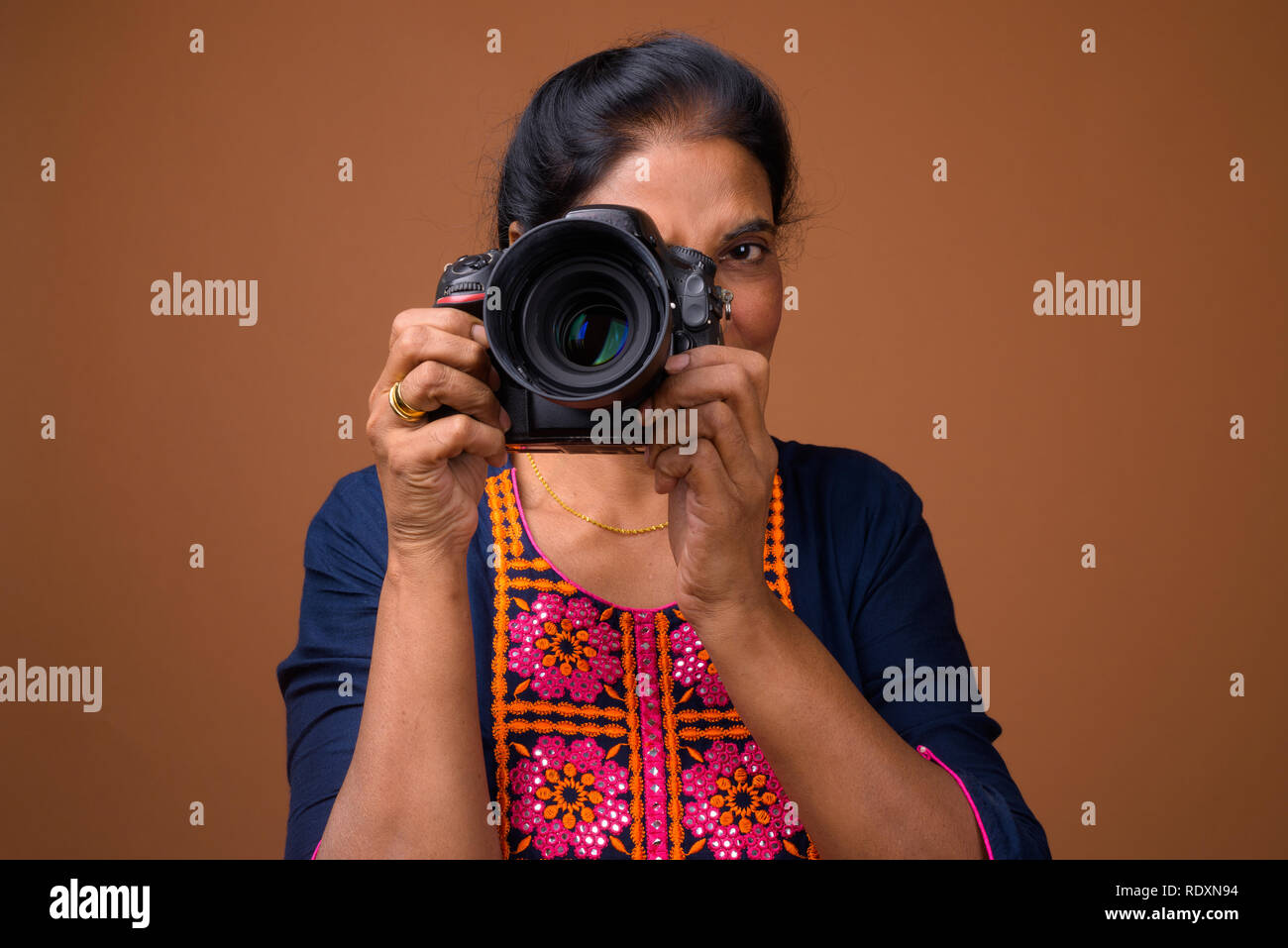 Mature beautiful Indian woman photographer using DSLR camera Stock Photo