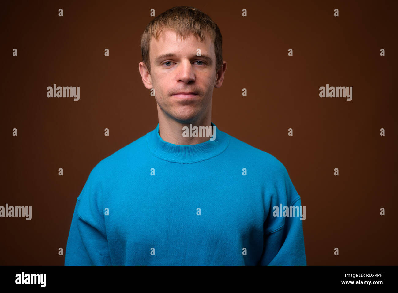 Man wearing blue sweater against brown background Stock Photo