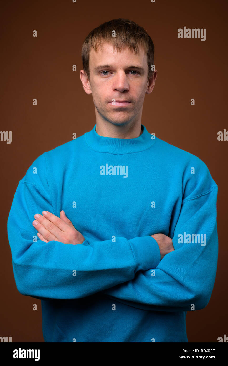 Man wearing blue sweater against brown background Stock Photo