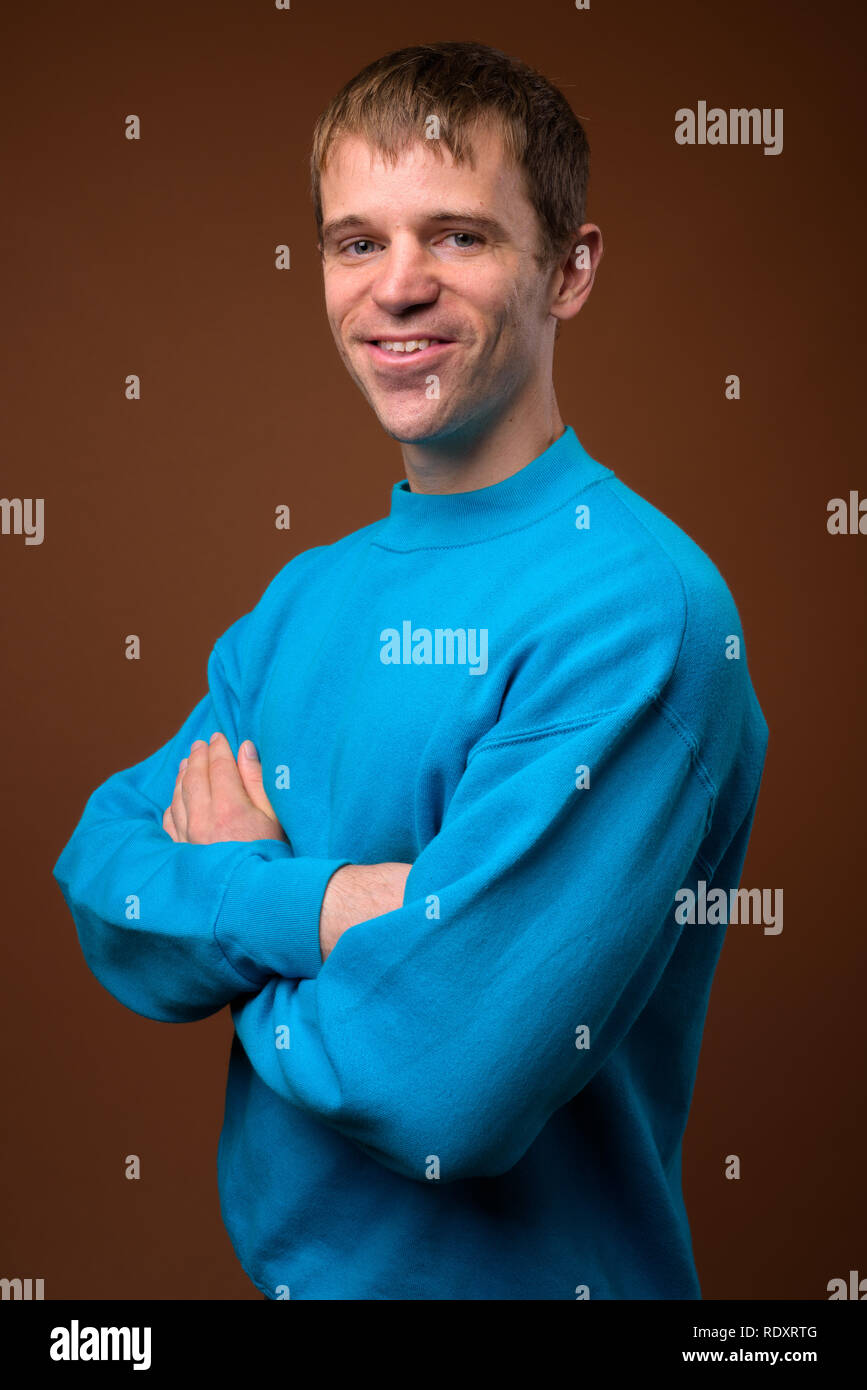 Man wearing blue sweater against brown background Stock Photo
