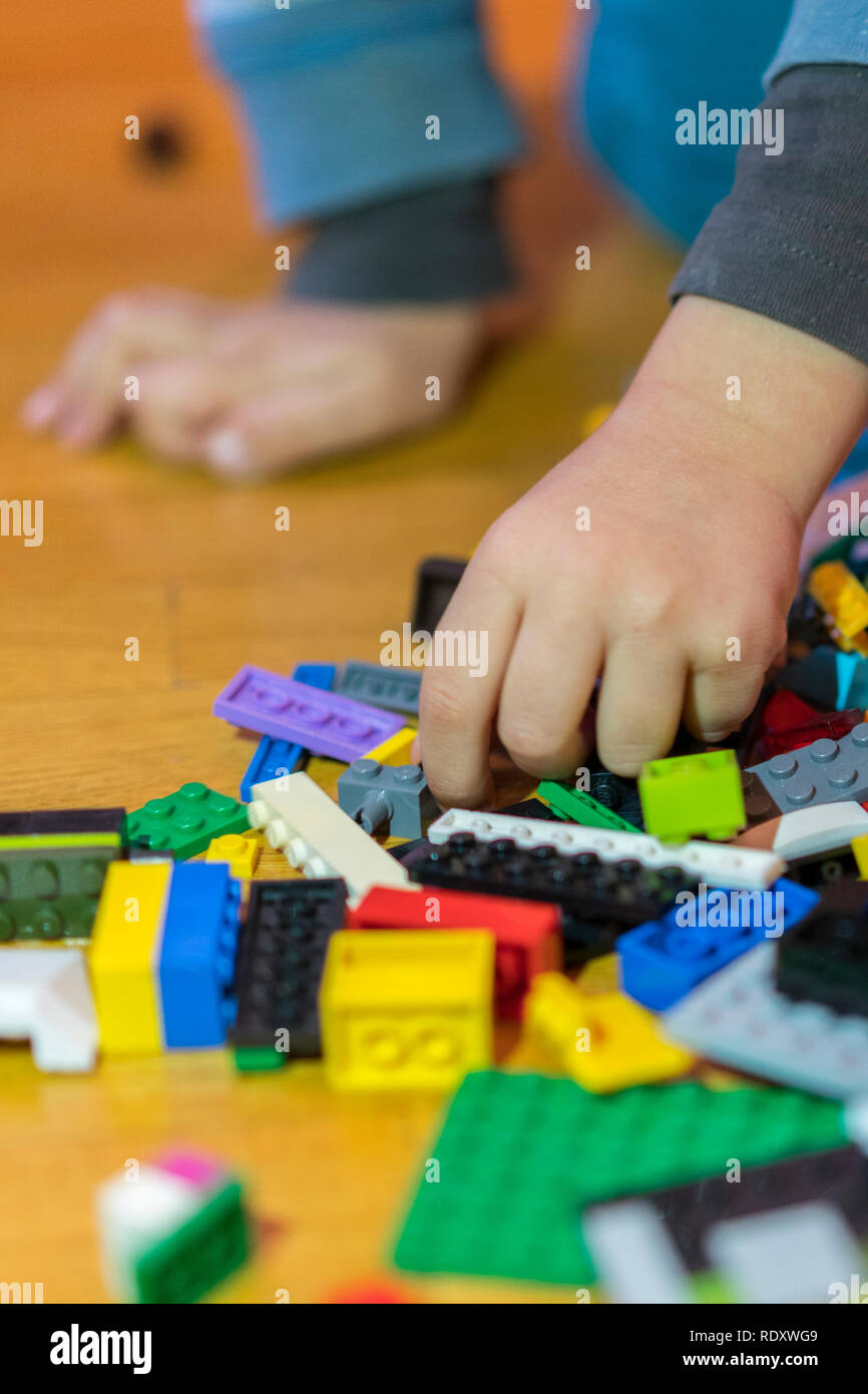 Close up of colorful plastic bricks on the floor. Early learning. Children's plastic constructor on the floor. Children's hands play a little construc Stock Photo