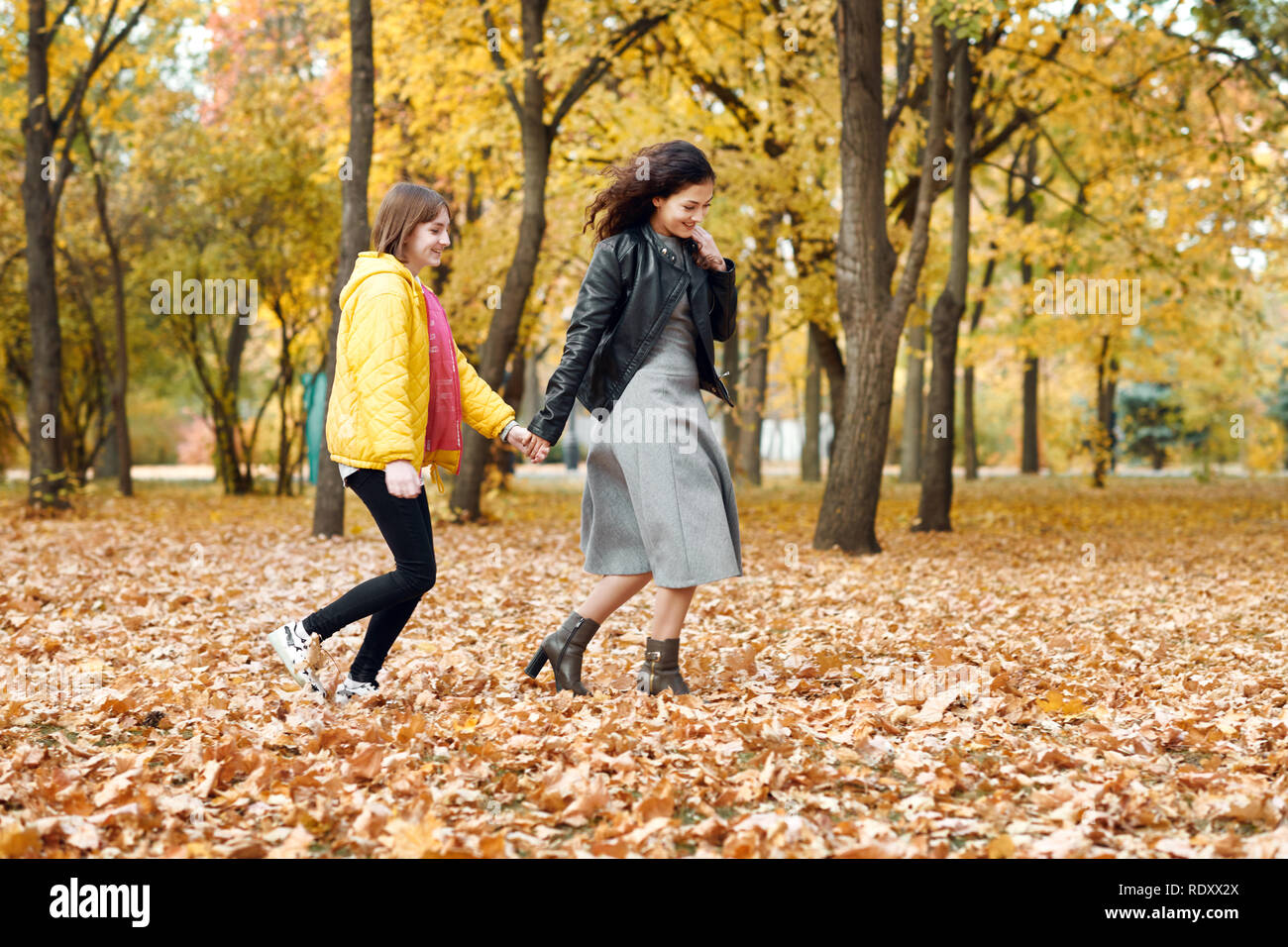 Two happy girls running in autumn city park Stock Photo - Alamy