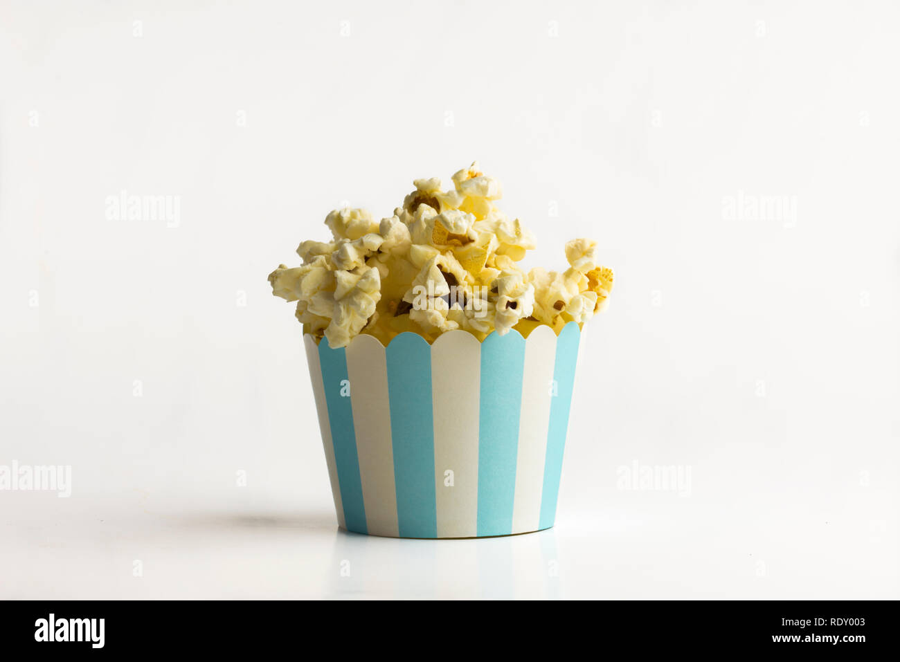 Popcorn in a small paper bucket on white background - a concept Stock Photo