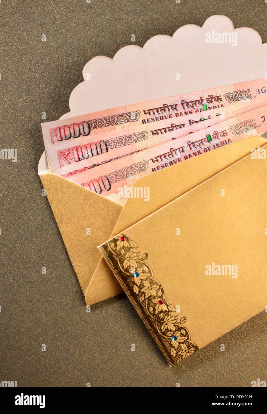 One thousand Indian Rupee notes in a golden envelope. Cash gifting. Stock Photo