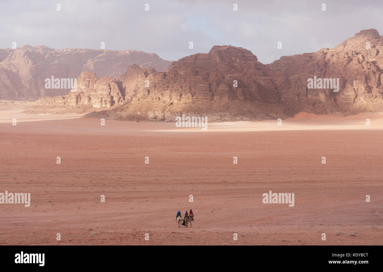Wadi Rum desert landscape in Jordan with tourists riding camels in the morning Stock Photo