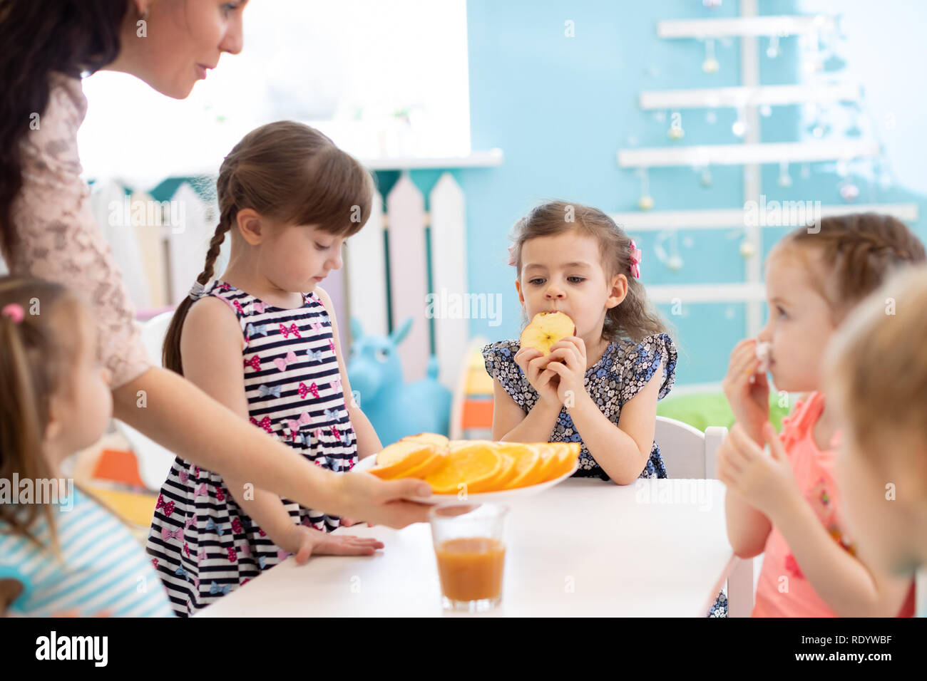 kindergarten teacher and preschoolers children having break for fruits and vegetables Stock Photo