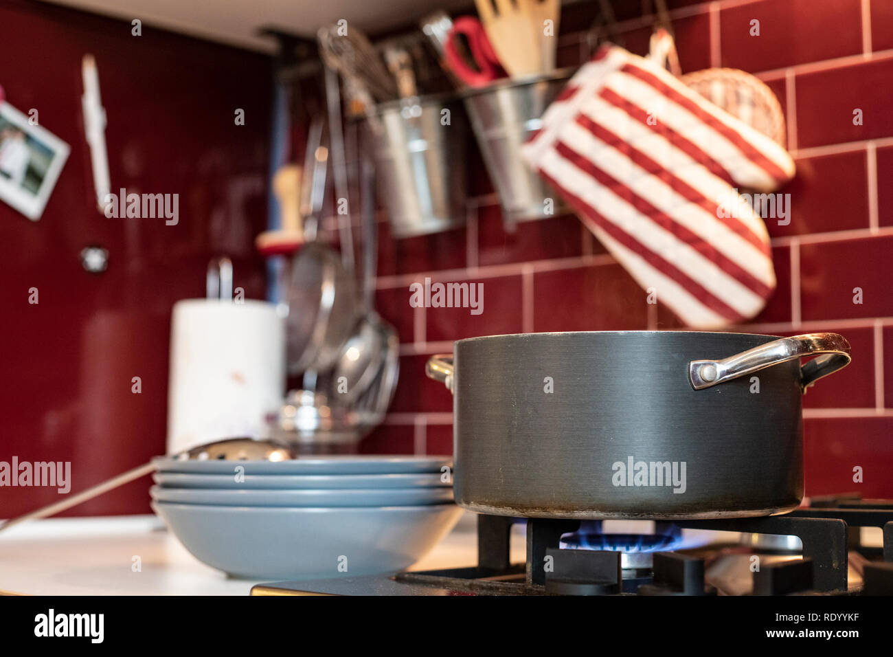https://c8.alamy.com/comp/RDYYKF/grey-cooking-pot-on-gas-stove-with-steam-releasing-and-blue-dishes-on-the-side-in-red-burgundy-classic-kitchen-with-tools-in-the-background-RDYYKF.jpg