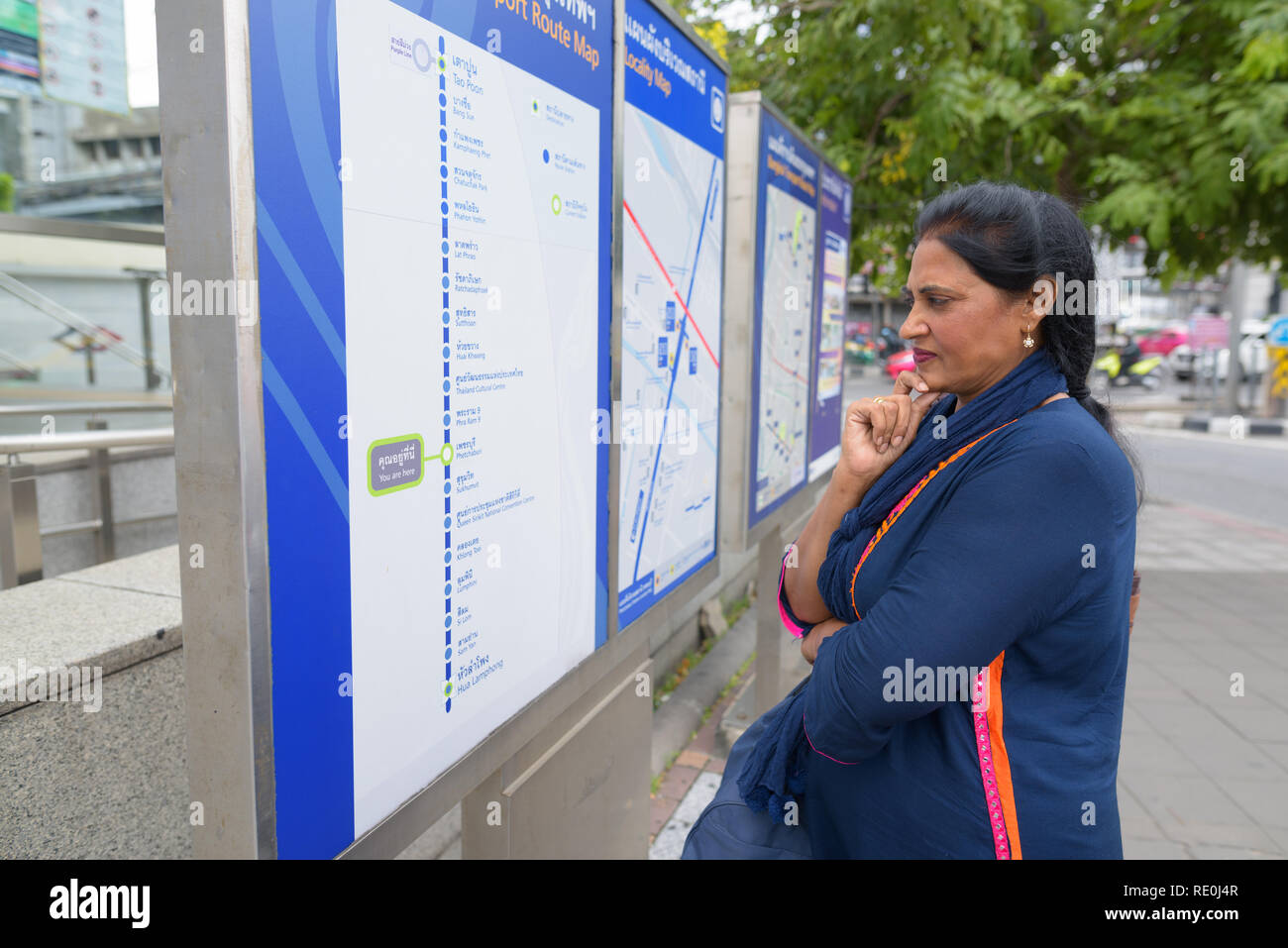 Mature beautiful Indian woman looking at train map outdoors Stock Photo