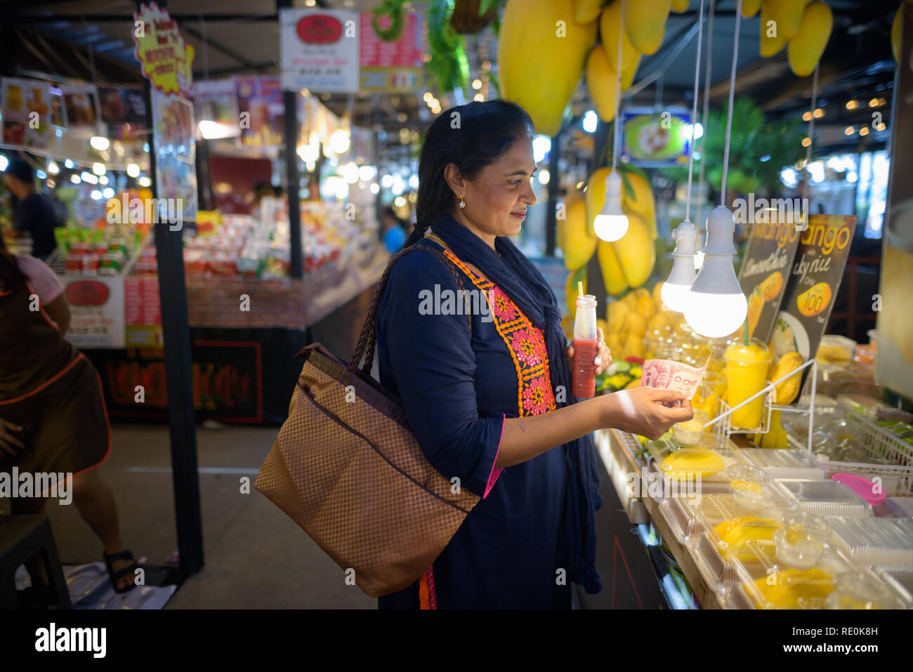 Mature beautiful Indian woman buying mango fruits in market Stock Photo