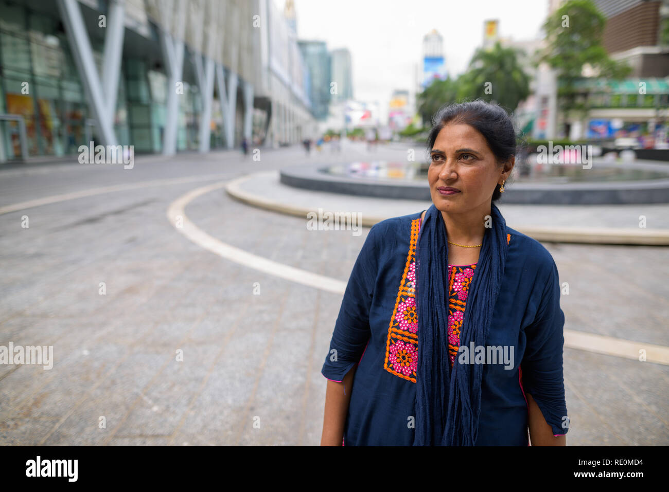 Mature beautiful Indian woman thinking in city Stock Photo