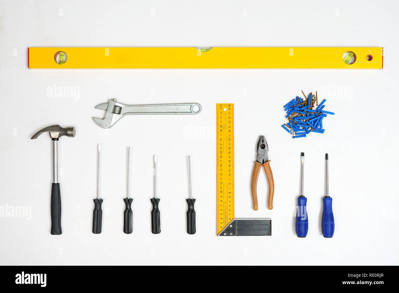 Flat lay of arranged screwdrivers with various tools and dowels with nails on white background Stock Photo