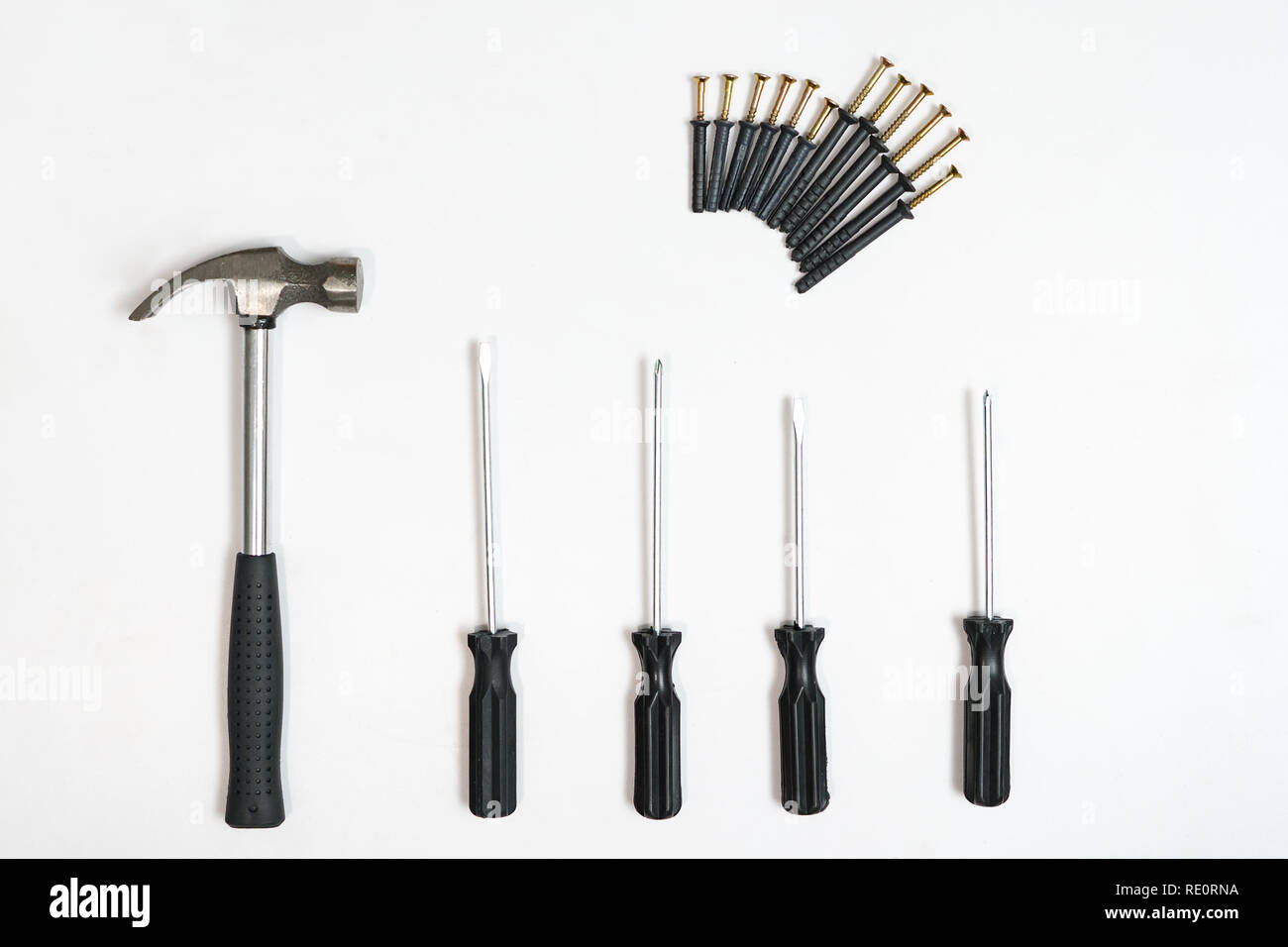 Top view of screwdrivers,hammer, screws and dowels on white backdrop