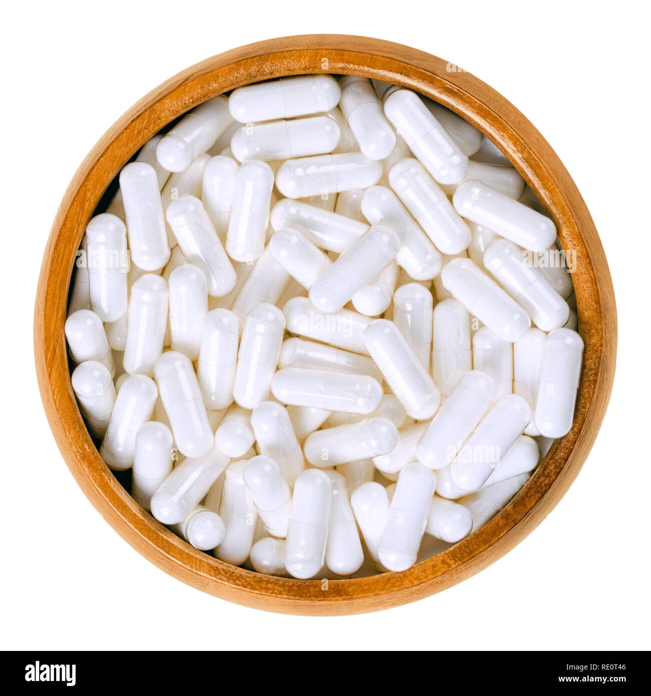 White food supplement capsules in wooden bowl. Hard shelled capsules, filled with powder, for example vitamin B12, cobalamin. Stock Photo