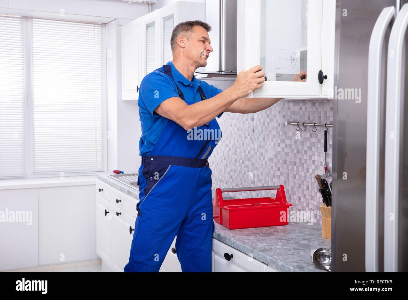 Side View Of Male Handyman Fixing Door Using Screwdriver In