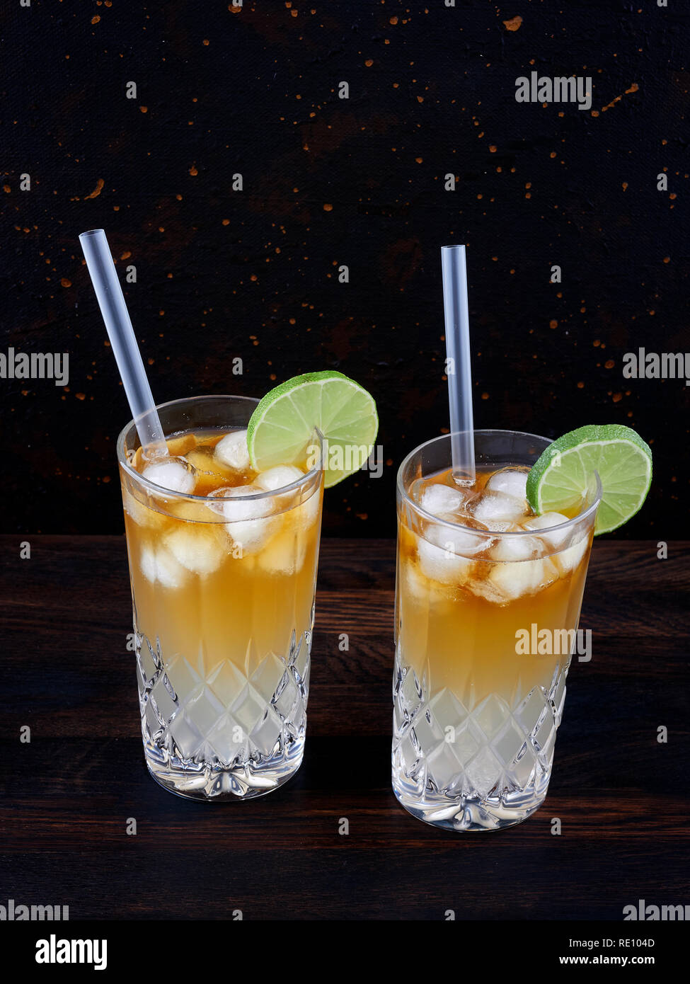 Dark 'n' stormy, a cocktail made using dark rum, ginger ale or beer, served in a highball glass filled with ice and garnished with a slice of lime Stock Photo