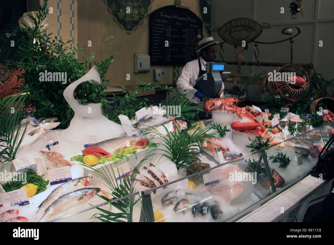 Salesman behind the showcase filled with fresh fish and seafood at Harrods department store in London, United Kingdom Stock Photo