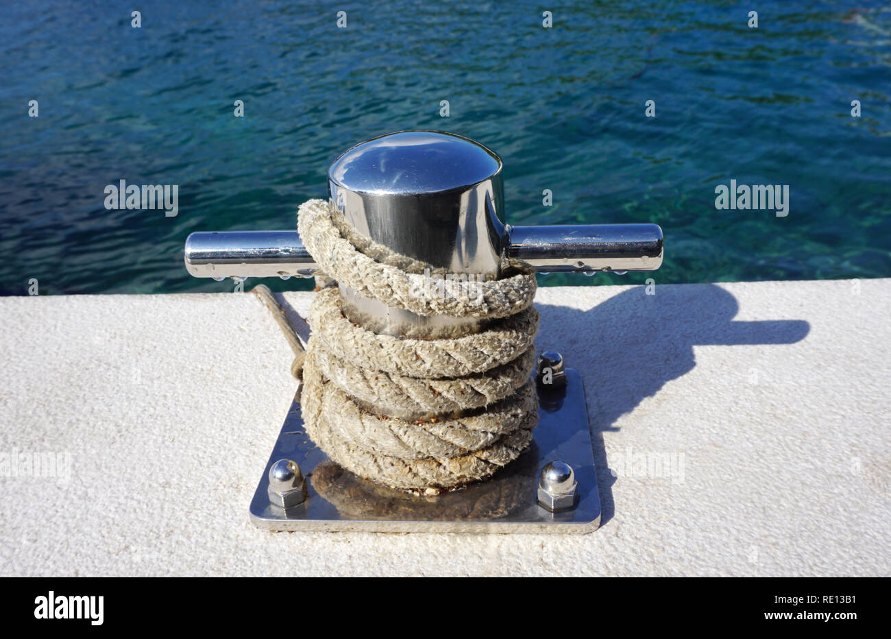 Mooring bollards with rope tide around by the blue color sea surface Stock Photo