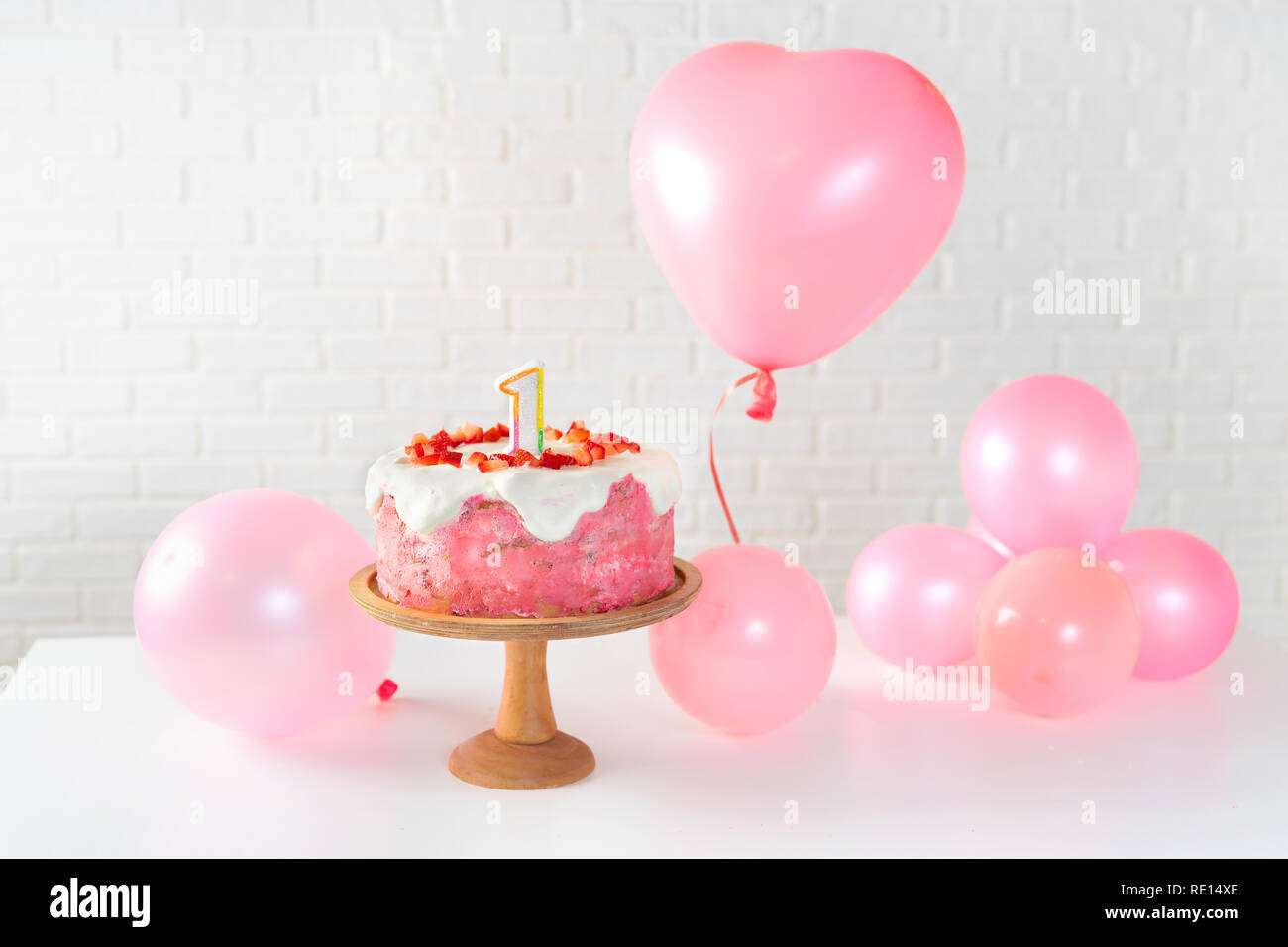 Strawberry cake with figure one and pink ballons on white background Stock Photo