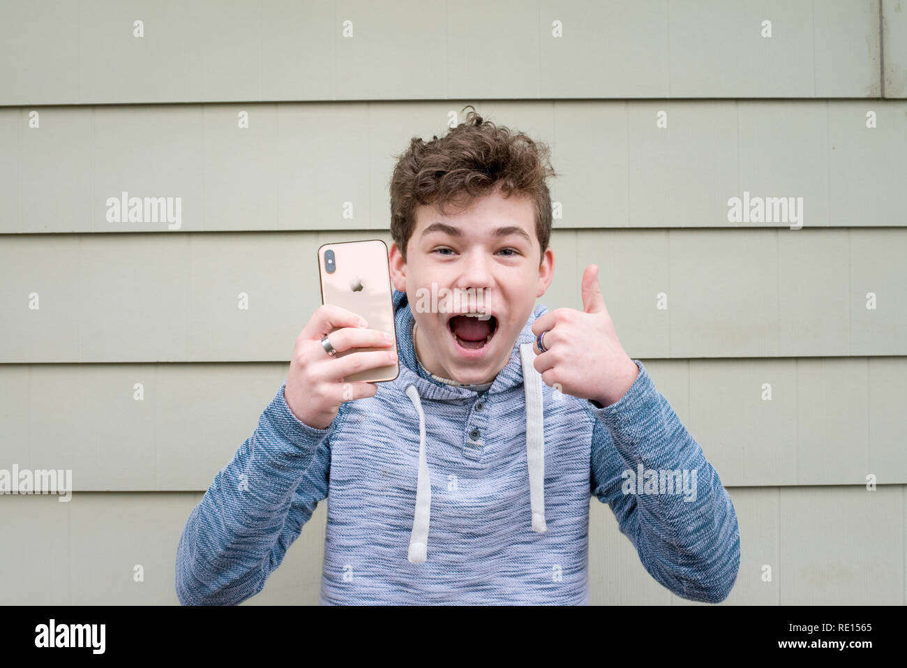 Male teenager giving thumbs up while holding his new Apple iPhone X ...