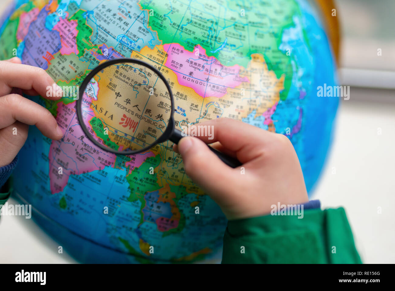 Zhongshan,China-February 7, 2018:kid looking at the map of China on a globe with magnifier. Stock Photo