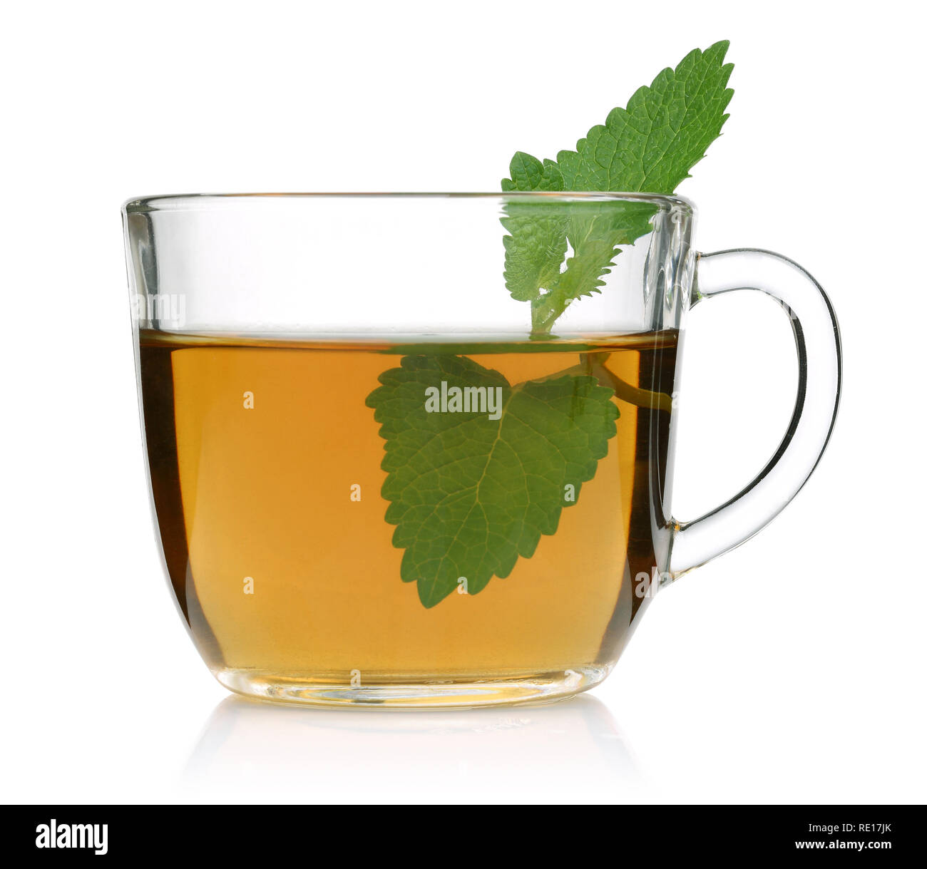 Melissa tea in a glass cup and green lemon balm leaves on white