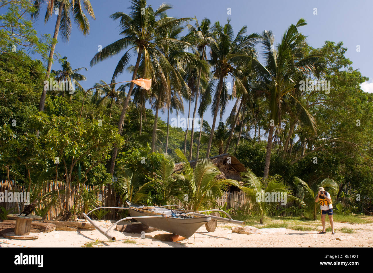 Tourist and a boat moored in the white sand of the island of Comocutuan. Palawan Philippines Stock Photo