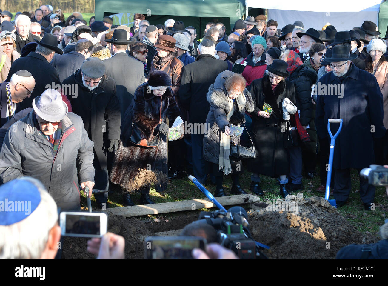 A group of survivors of the Holocaust throw earth onto the coffin with the remains of six