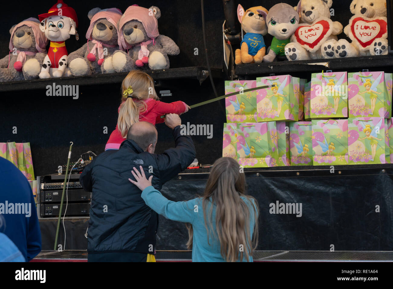 Young girl being helped by father to win a fairground prize on a family day out at a funfair in York, North Yorkshire, England. Stock Photo